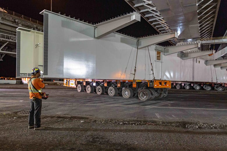 Diesel engine-powered trailers move a gigantic box girder assembly into place under the New Champlain Bridge in Montreal, Canada.